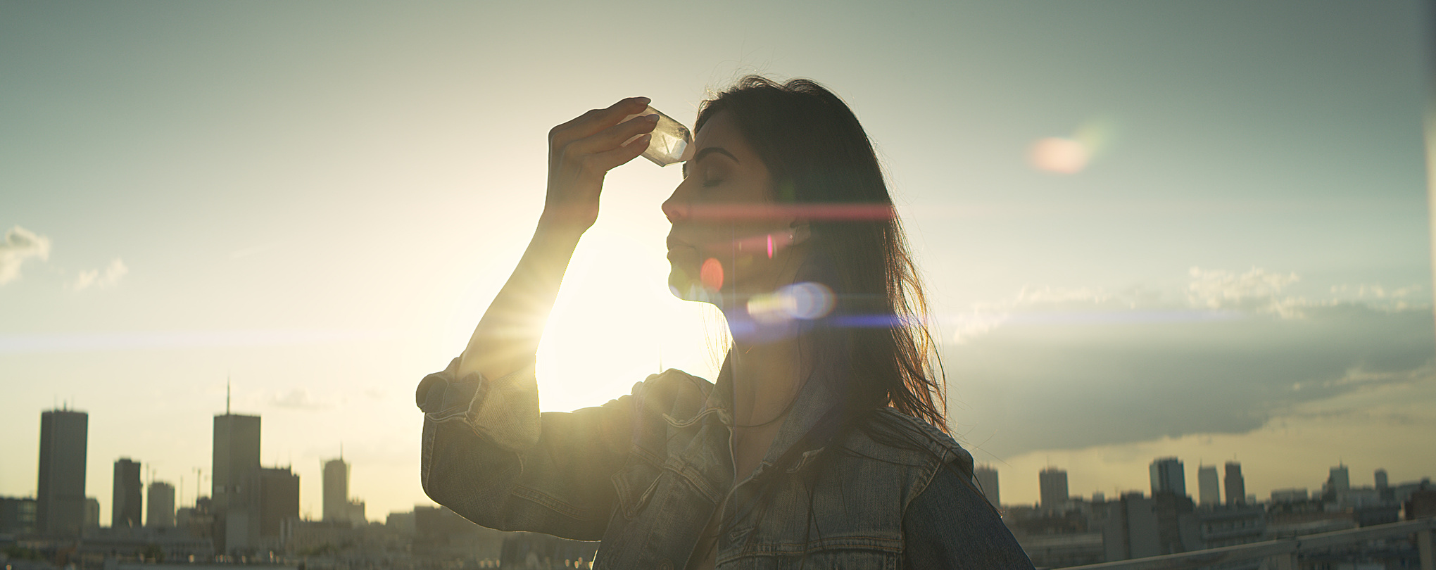 Crystal healing. Woman on a rooftop with city panorama